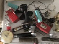 Photo showing vintage electric fan and various flashlights arranged together
