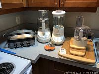 Countertop with Cuisinart griddler, dual blender, food processor, blade attachment, and three bamboo cutting boards