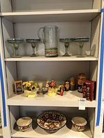 Full lot on shelves showing margarita set, nesting dolls, tarot deck, small flower pots and Pier 1 bowls