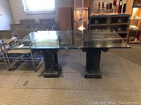Full view of the glass topped dining table with two marble column bases and additional glass top on the table