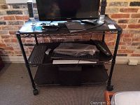 Front view of metal wire rack with shelves, black PDF covers on shelves, items shown on rack not included.