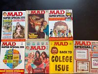 Seven vintage Mad Magazine issues laid out on a surface showing front covers with distinct colorful satirical and comic artwork.