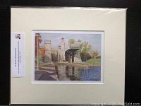 Full view of the art print in white matting sealed in plastic packaging, showing the lift lock scene