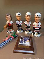 Four Team Canada hockey bobbleheads with Tie Domi plaque and Toronto Maple Leafs pencils on display.