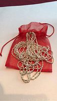 Necklace arranged on red drawstring pouch on white background showing multiple strands.