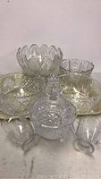 View showing all crystal bowls and dishes arranged on a flat surface, including footed covered dish, large bowls, pedestal bowl, cream and sugar set, and two small bowls.