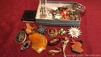 Photo showing full lot with brooches spread out and box containing additional jewelry including pendant and bracelet.