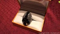 Large hematite ring with black and clear crystals in jewelry box showing front view.