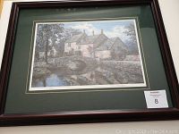 Framed lithograph of a stone bridge and house over river with matting and glass.