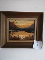 Frontal view of the framed oil painting showing sunset mountain lake scene.