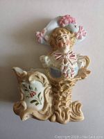 Front view of the porcelain bisque bust figurine showing detailed handpainting on the face, hat, and clothing with floral decoration on the base.