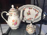 Full set showing coffee pot, sugar bowl, and reticulated oval plate with floral designs and gold accents