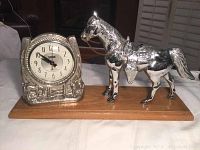 Front view of vintage mantle clock with chrome clock housing and horse figurine on wooden base.