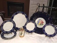 Full set of plates and decorative bottle arranged on a white cloth, showcasing overall condition and scale.