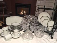 Photo showing full set of Rosenthal china plates, mugs, saucers, platter and arranged crystal pieces including wine decanter, cake plate, vase, sugar bowl, and creamer.
