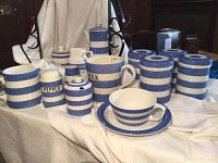 Group shot of all blue and white striped pieces including coffee pot, milk pitcher, storage jars, shakers, plate, teacup and saucer
