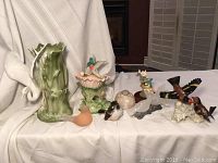 Front view of green jade bird carving on marble base and a collection of various ceramic and porcelain bird figurines arranged in a row