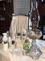 Full view of six vintage oil lamps, showing various styles and glass types including hobnail white, clear glass with ornate base, green uranium glass miniatures, and Victorian styles.