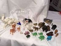 Assorted colored glass, stone, brass, and marble animal figurines arranged on cloth