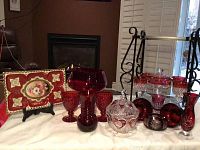 Full lot showing variety of cranberry/red ruby crystal glassware and hand painted Vienna tray displayed on white cloth.