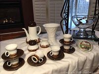 Full view of the coffee set with cups, saucers, creamer, lidded pot, sugar bowl and porcelain trinket dish on table