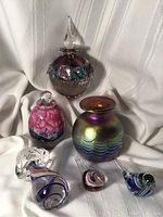Lot of signed vintage artisan glass perfume bottles and a Murano jellyfish paperweight displayed on white fabric backdrop.