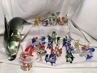 Overall view of large dolphin sculpture and mini glass animals on white cloth