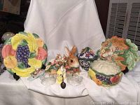 Overview of all ceramic pieces including fruit plate, bunny figurine, candy dish, leaf canape plate, duckling planter, and glass egg cups.