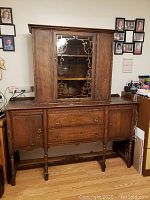 Full front view of antique buffet hutch with glass front upper cabinet, drawers, and cabinets below