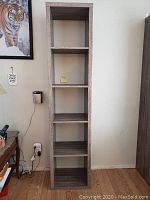 Front view of tall cube style book shelf against wall with five compartments visible.