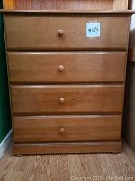 Front view of a solid wood dresser with four drawers and round wooden knobs. Natural wood finish. A sticker labeled '#125' is visible on the top drawer.