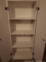 Inside view of one white storage cupboard showing three internal shelves, two of which are adjustable.