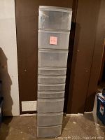 Front view of tall plastic storage drawer system with eight transparent drawers in light grey frame.
