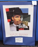 Framed autographed Garth Brooks poster with geometric styled image and blue matte, no glass in frame.