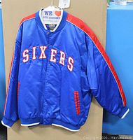 Front view of the vintage Philly 76ers blue nylon jacket with red and white accents. 'SIXERS' embroidered on chest.