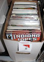 Photo of a cardboard comic book storage box with comic books inside, showing The Further Adventures of Indiana Jones by Marvel on top