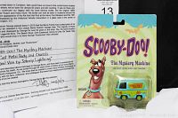 Close-up of the Certificate of Authenticity and Scooby-Doo Mystery Machine van packaging displaying item details and provenance.