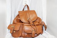 Front view of brown faux leather backpack showing main flap with buckle and three front buckle pockets.