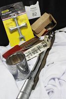 Photo showing various hand tools arranged on white cloth including boxed General Plug Wrench, offset screwdriver, socket tool, files, and wrenches.