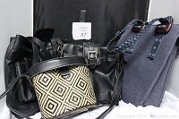 Four handbags grouped showing different styles and colors: navy blue cloth tote, black leather-like purse, patterned crossbody, and woven shoulder bag