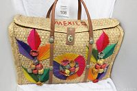 Front view of woven basket tote bag showing colorful yarn flowers and geometric designs with leather handles and clasp and 'MEXICO' text embroidered.