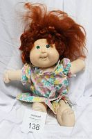 Front view of 1987 Cabbage Patch Doll sitting showing full doll, red curly hair, and floral dress