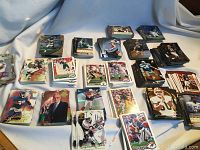 Wide shot of multiple stacks of basketball cards spread on cloth background, frontline cards showing various players and styles.