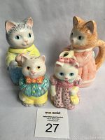 Front view of four vintage Avon 1992 animated cat collectibles including two large cream and sugar cats in clothing and two small salt and pepper shakers with corks.