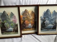 Three framed acrylic paintings on canvas depicting the same scene in different seasons: Spring, Fall, and Winter, laid out side-by-side showing size and relative condition.