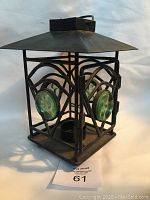 Black metal lantern candle holder showing the open door revealing the candle holder interior and green glass marble accents on side panels.