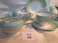 Photo of tea cups, saucers, creamer, and sugar bowl showing the gold rim and mint green band pattern