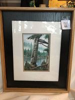 Full view of framed and matted print showing the raven on totem pole with forest and lake background, wood outer frame with black inner frame, white matting