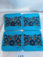 Four square turquoise coasters with detailed Indigenous art by Norval Morrisseau; coasters have cork backing.