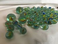 Scattered clear glass marbles with colored swirls on a white fabric background.